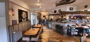 a restaurant with tables and a bar with a person in the background at Hotel Restaurant The Kings Head Inn in Voeren