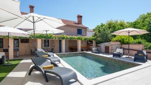 a pool with chairs and umbrellas next to a house at Villa Katarina by Villas Guide in Barban