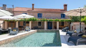 a pool with chairs and umbrellas in front of a house at Villa Katarina by Villas Guide in Barban