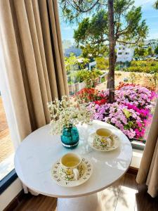 a table with two cups of coffee and flowers on it at Arora Home Pleiku in Pleiku