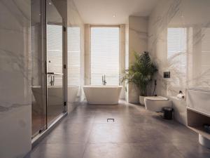 a bathroom with a tub and two toilets and a sink at Villa 72 RAK in Ras al Khaimah