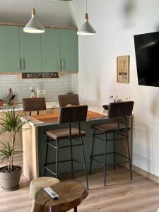 a kitchen with green cabinets and two bar stools at GuestHouse "Shtëpia ime" in Përmet