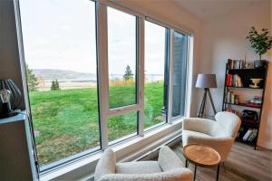 a living room with windows with a view of a field at Terrace Condo with River View and Pool in Baie-Saint-Paul +52 photos