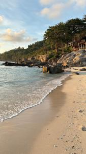 a sandy beach with rocks and the ocean at Lemon Grass Chalets in Kampong Pasir Panjang +26 photos