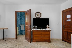 a room with a tv on a wooden dresser and a bathroom at Chambres D'hôtes - Le Mas Du Rocher in Hyères