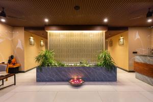 a lobby with a fireplace and plants in the middle at The Golden Tusk By Ivory Destinations in Rāmnagar +196 photos