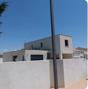 a white house with a wall and a pole at Belle villa à la mer in Sérignan +5 photos