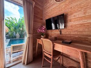 a dining room with a table and a tv and a window at Kubu Dimel Suites and Villas Resort in Nusa Dua