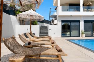 a group of chairs and umbrellas next to a swimming pool at Interni Villa by A&D Properties in Porto Rafti