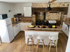 a kitchen with white cabinets and a island with bar stools at Gîte champêtre LA SUITE Limousin in Saint-Yrieix-la-Perche
