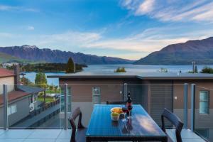 a table on a balcony with a view of a lake at LakeRidge Queenstown by Staysouth in Queenstown
