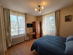 a bedroom with a bed and a desk and two windows at La demeure de Chambord in La Ferté-Saint-Cyr