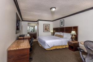 a hotel room with a bed and a desk at Budget Host Inn Florida City in Florida City