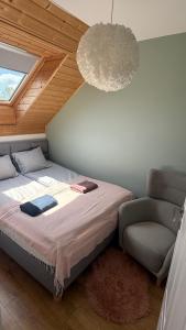 a bed and a chair in a room with a ceiling at Liwia Park Green House in Niechorze