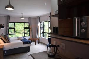 a bedroom with a bed and a kitchen with windows at Sleep84 in Dullstroom