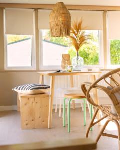 a dining room with a table and chairs and windows at Zomerhuisje Chalet in Voorthuizen