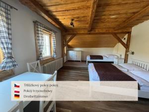a bedroom with two beds and a wooden ceiling at Penzion Muštelka in Rokytnice nad Jizerou