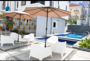 a group of white chairs and umbrellas next to a pool at Lekki Waterfront Terrace shortlet with Oceanview, Attendants and private Jetty in Lagos