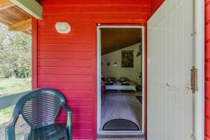 a red house with a green chair in the doorway at Le Cabanon Mios in Mios +13 photos