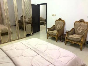 a bedroom with two chairs and a bed and a mirror at Masirah oyster in Ḩilf
