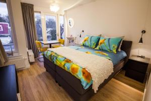 een slaapkamer met een bed met een kleurrijk dekbed bij Puur Geluk in Groningen