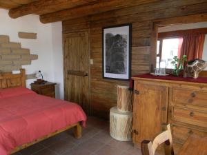 1 dormitorio con cama roja y ventana en La Troje de Adobe en Creel