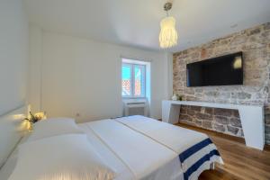 a bedroom with two beds and a tv on a stone wall at Villa Majestic with heated pool and rooftop terrace in Bol