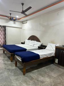 a bedroom with two beds with blue sheets and a ceiling at Srilakshmi Residency in Tirupati