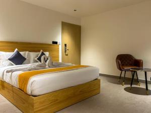 a bedroom with a large bed and a chair at Hotel Orelio - Airport Hotel in Bangalore +4 photos