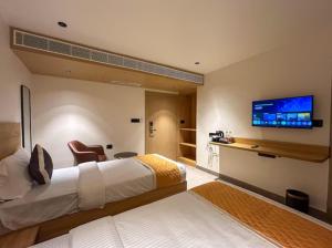 a hotel room with two beds and a flat screen tv at Hotel Orelio - Airport Hotel in Bangalore