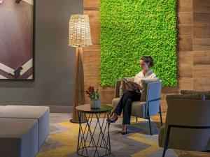 a woman sitting in a chair in a living room at Novotel Curitiba Batel in Curitiba