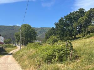 a dirt road with a fence and mountains in the background at Posada Inés in Castro-Urdiales