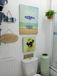 a bathroom with a toilet and pictures on the wall at Cosy Seaside Snug in Helensburgh +2 photos