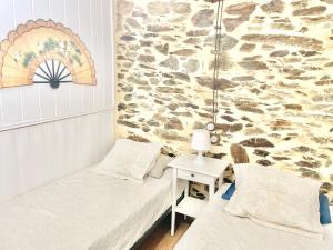 a room with two beds and a stone wall at El Rincón de Salsipuedes in Cudillero