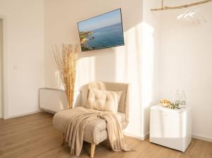 a living room with a chair and a tv on the wall at Casa Del Barone Suites in Monopoli