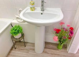 a white sink in a bathroom with pink flowers at Cosy Seaside Snug in Helensburgh