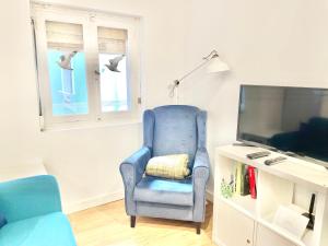 a living room with a blue chair and a tv at El Rincón de Salsipuedes in Cudillero