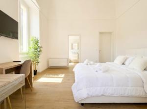 a white bedroom with two beds and a desk at Casa Del Barone Suites in Monopoli