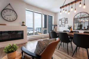 a dining room with a clock and a table and chairs at 204 - Luxury Obsidian Condo - Elegance & Pool in Baie-Saint-Paul +50 photos