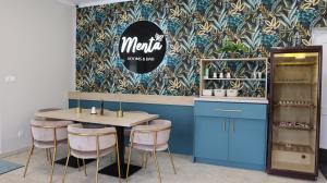 a dining room with a table and chairs and a wall at Menta Rooms & Bar in Kapuvár