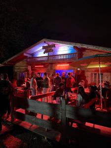 a group of people standing outside of a bar at night at Wies'n Camp in Munich