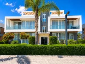 a building with a palm tree in front of it at Nothern Cyprus Four Seasons Life Collection Apartments & Lofts Seafront in Ayios Dhometios