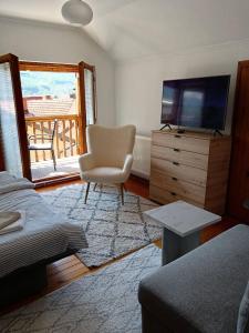 a living room with a television and a chair at Goražde-Centar Apartment in Goražde