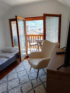 a living room with a bed and a chair and a balcony at Goražde-Centar Apartment in Goražde