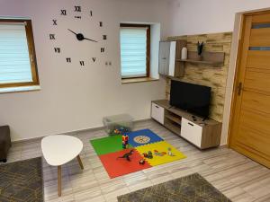 a living room with a tv and a clock on the wall at Zója Apartmanház in Nagykanizsa +25 photos