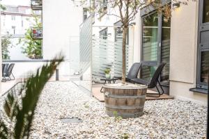 a patio with chairs and a tree in a barrel at Schwabinger Wahrheit by Geisel in Munich