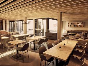 a restaurant with wooden tables and chairs and windows at Schwabinger Wahrheit by Geisel in Munich