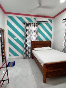 a bedroom with a bed and a striped wall at Radiance Inn in Jaffna
