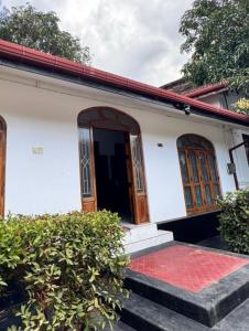 a white house with a door and a red porch at Radiance Inn in Jaffna