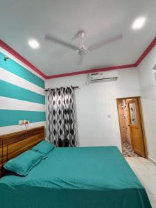 a bedroom with a green bed and a striped wall at Radiance Inn in Jaffna